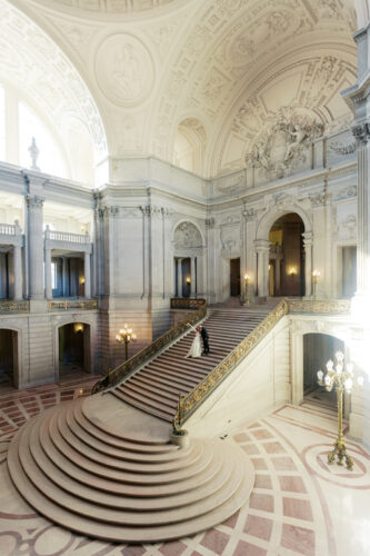 Beautiful couple at the staircase of San Francisco City Hall. A wide shot of the whole city hall