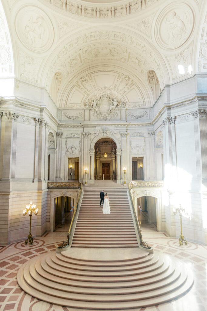 A wide picture of SF City Hall taken from the Mayor's Balcony. It shows a couple going up the stairs in an empty city hall.