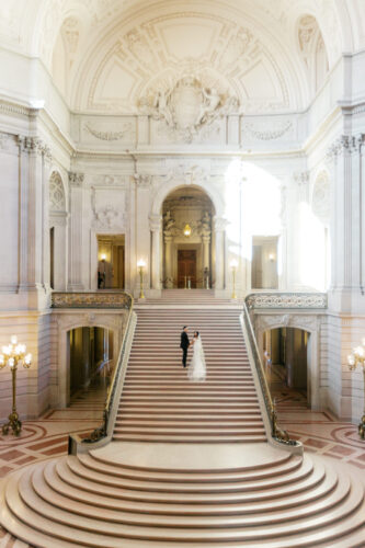 Beautiful couple at the staircase of San Francisco City Hall. A wide shot of the whole city hall