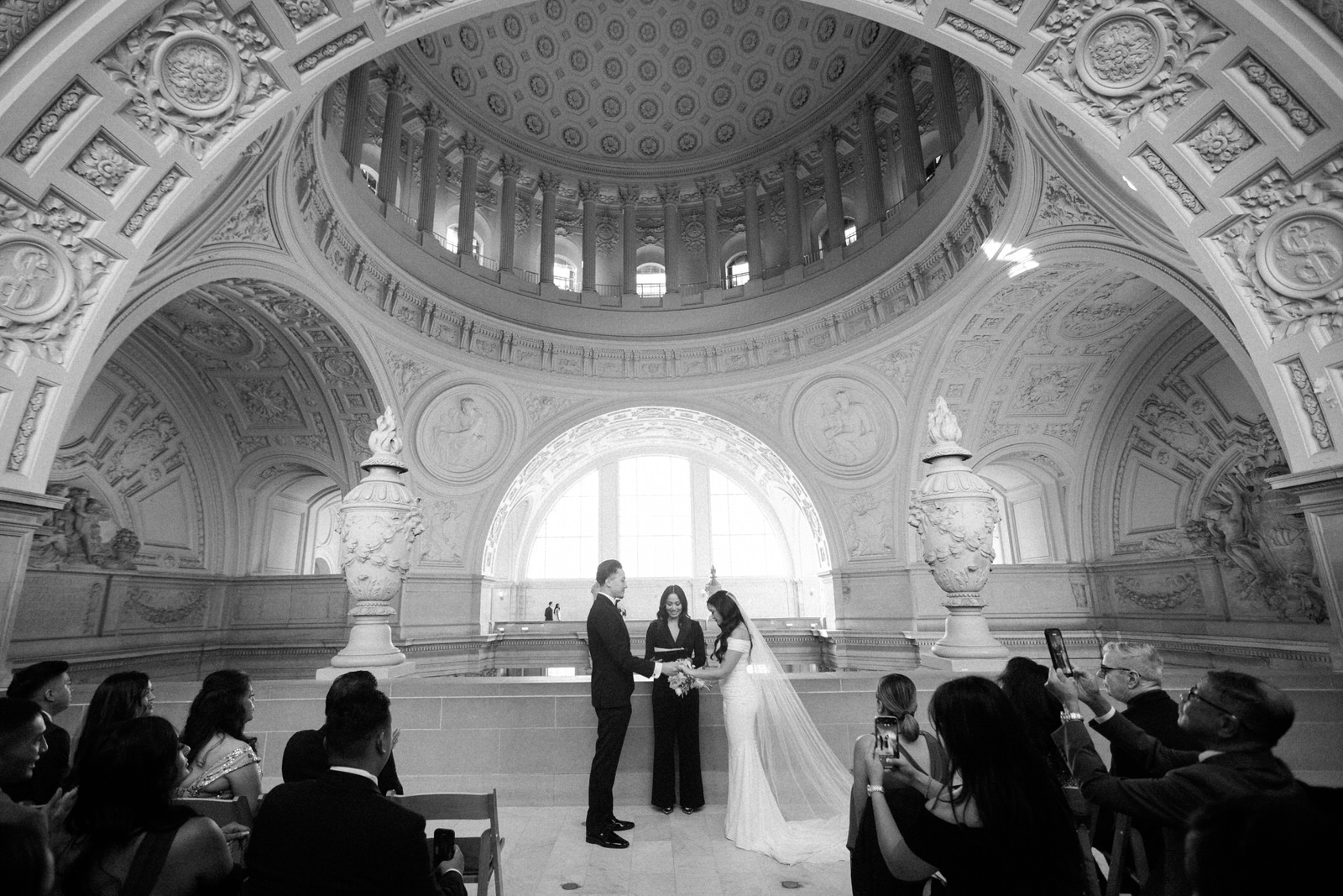 A black and white picture of a couple getting married at the 4th floor balcony at SF city hall