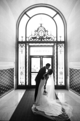 A couples silhouette in front of the exit door at city hall captured by a San Francisco City Hall wedding photographer