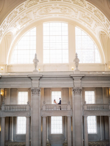 A wide shot of city halls interior and floors with a couple standing on one of the floors from a distance.