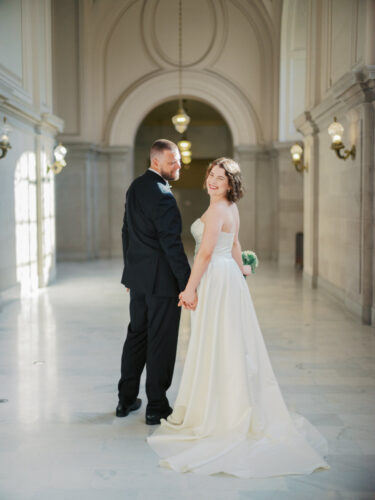 A couple on the 4th floor of city hall looking backwards towards the camera. 