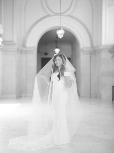 A beautiful bride with her cathedral veil over her on the 4th floor at city hall captured by a San Francisco City Hall wedding photographer