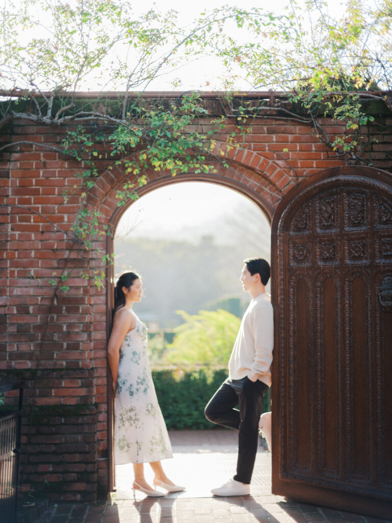 A couple doing their engagement photos not far from san francisco at Filoli Gardens in front of the wooden door. 