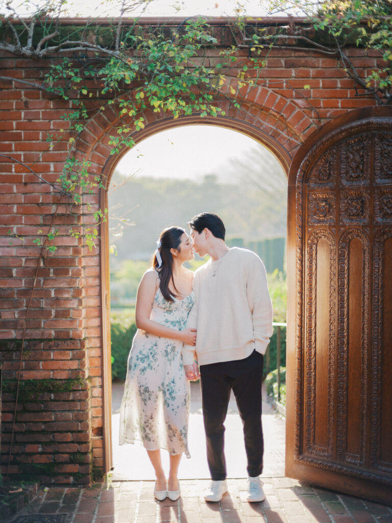 A couple doing their engagement photos at Filoli Gardens in front of the wooden door