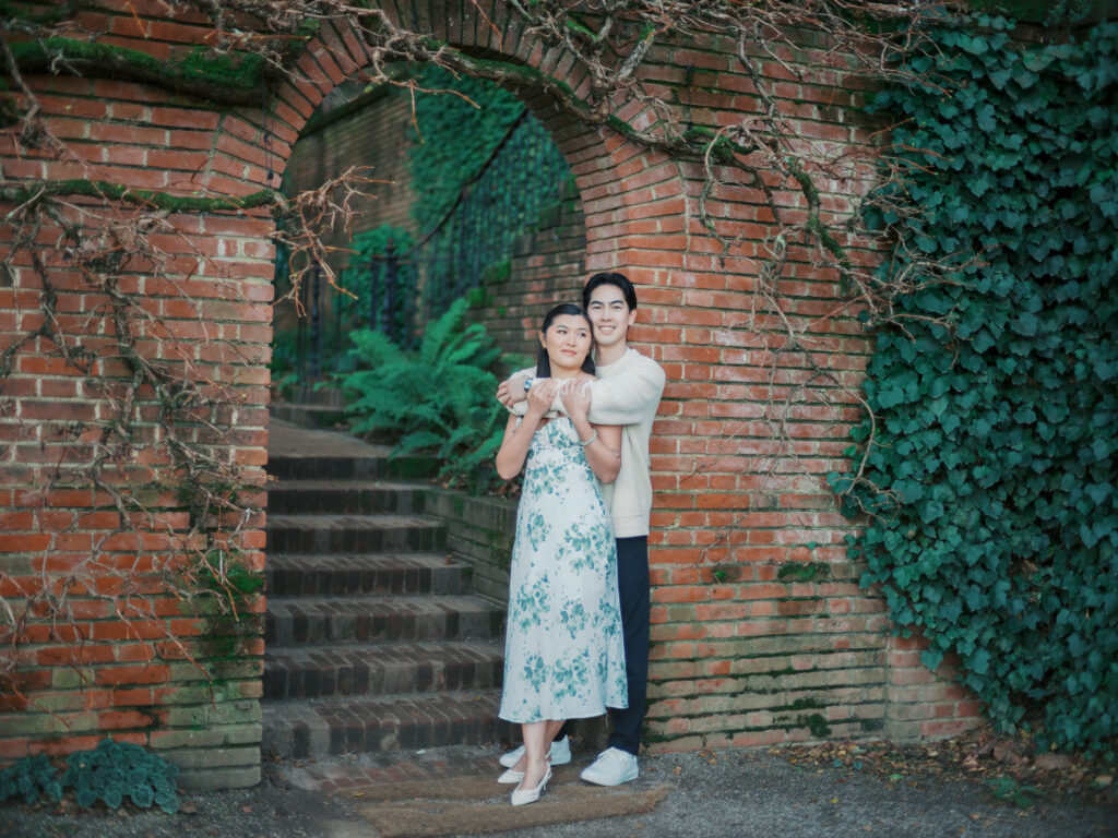 A couple doing their engagement photos not far from san francisco at Filoli Gardens underneath the brick masonry 